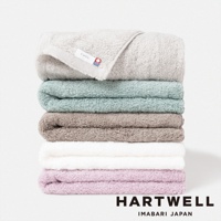 疊放的 CUOL 今治柔彈美肌毛巾，共六種顏色：淺灰、薄荷綠、淺棕、白色、淡紫色，以及最上方一條帶有品牌標籤的淺灰色毛巾。