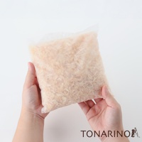 雙手捧著一個半透明的淺米色布袋，袋內裝滿了淺棕色的檜木屑。