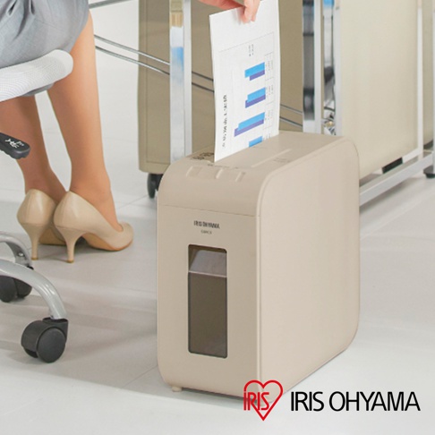 一台米色超靜音極細保密碎紙機，上面寫著 IRIS OHYAMA 的品牌標誌，一位女士正將文件放入碎紙機中。