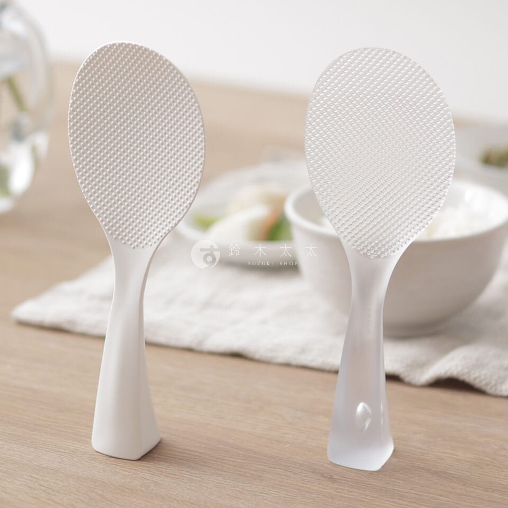 MARNA 站立式飯匙，白色，具有獨特壓紋表面，不易沾黏米飯，可保持桌面整潔，兩個飯匙並排放在淺色布料上，背景是碗裝米飯。