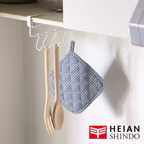 白色金屬製免鑽櫥櫃活動勾掛架，裝有五個彎鉤，掛有兩個木製湯勺和一個藍白條紋的隔熱手套。