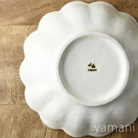 白色陶瓷花型主食盤，邊緣有明顯的波浪狀凹凸紋路，盤底中央有日文品牌標誌及「Japan」字樣。