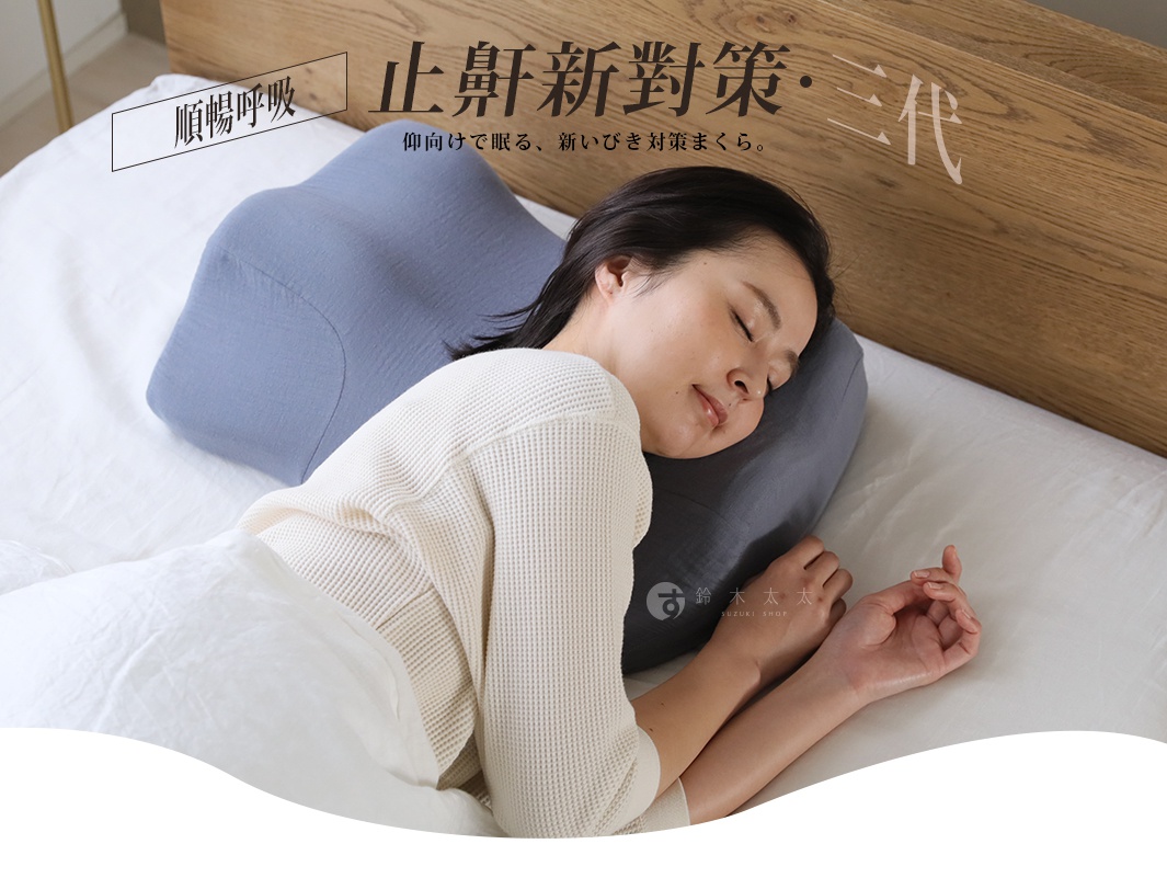 灰色布面止鼾枕，具有特殊弧度設計，適合側睡和仰睡，枕套材質細緻，搭配白色床單和木質床頭板。