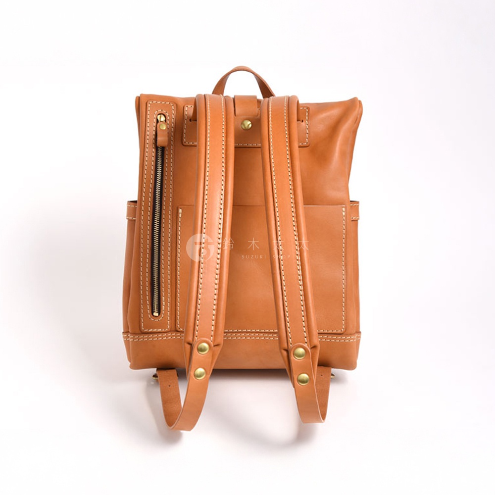 職人手作皮革雙口袋折蓋後背包，棕色皮革材質，設有雙肩帶、頂部提把、側邊拉鍊口袋和後方敞口口袋。