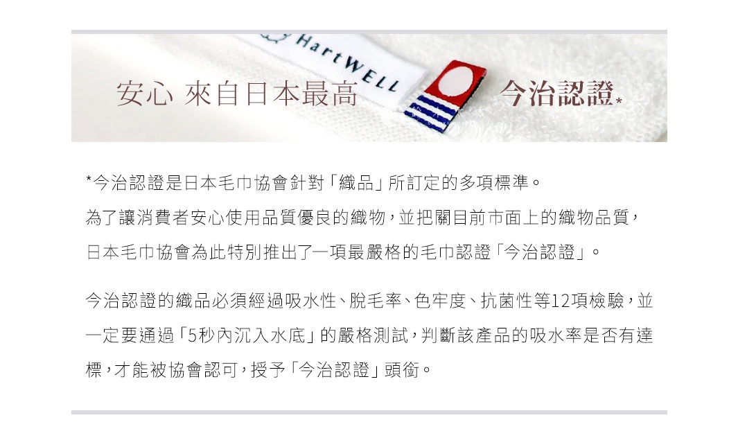 一條純白色厚手毛巾，標籤上印有「HartWELL」字樣，以及紅藍條紋的「今治認證」標誌。