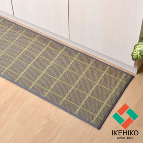 藺草編織的長方形廚房地墊，帶有網格圖案，顏色為棕色與淺綠色線條，四周鑲有深藍色滾邊，放置於木質地板上。