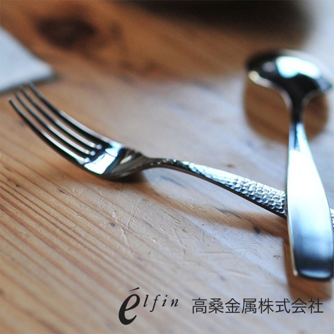 日製不鏽鋼餐叉，帶有錘目紋飾，銀色金屬光澤，置於木質桌面。