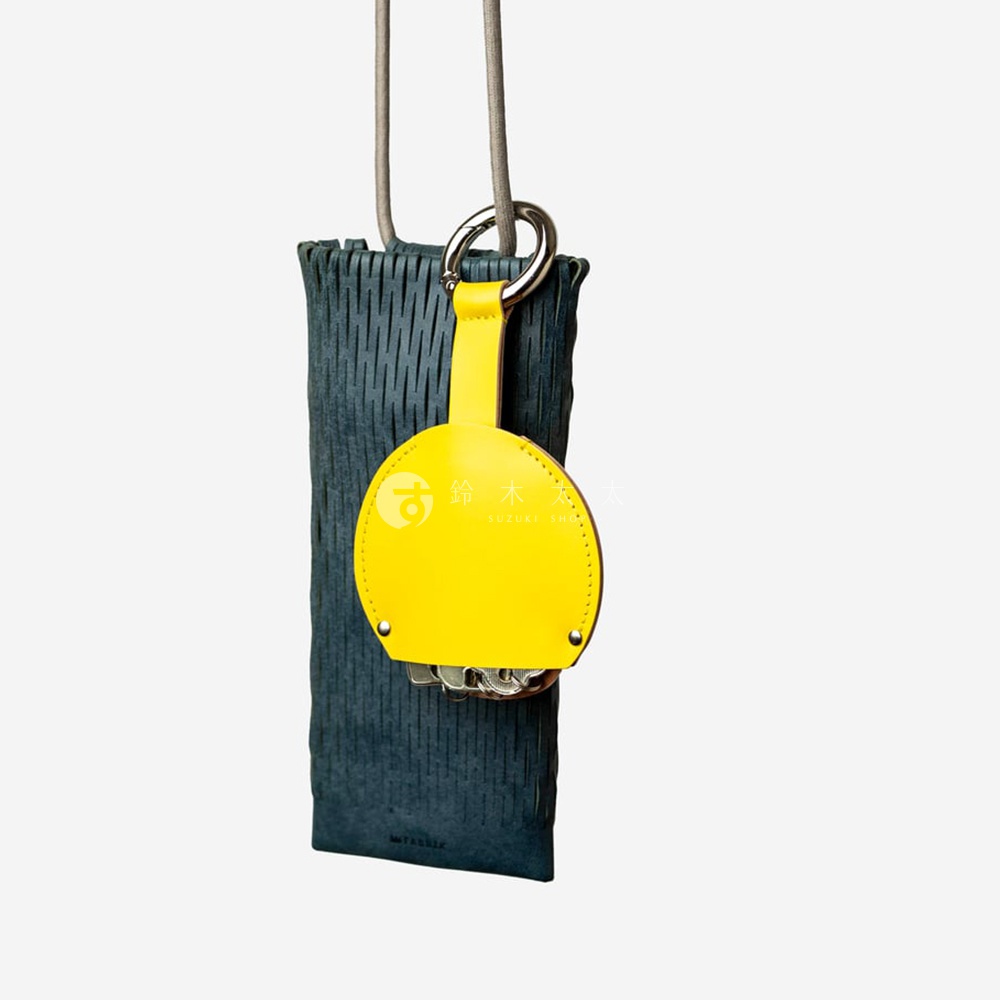 FABRIK 皮革圓型收納鑰匙圈，側邊有紋理，附有黃色皮革掛飾，上面印有品牌標誌和日文，掛繩與銀色金屬圈連接，下方可見鑰匙串。