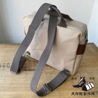 犬印純綿帆布三用橫式側背包，米白色帆布材質，搭配深棕色皮革飾邊，設有兩條灰色寬版織帶提把及一條可拆卸肩背帶。