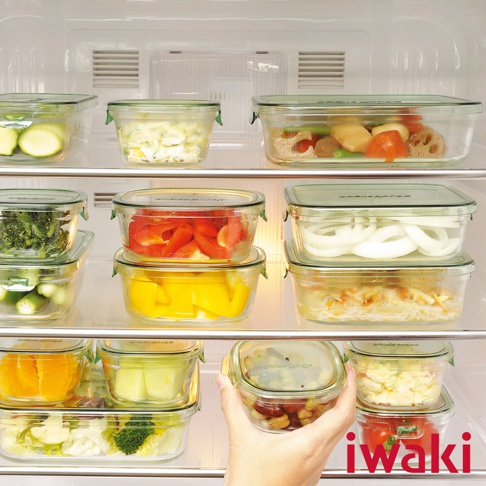 耐熱玻璃方形微波保鮮盒，內含各式食材，如櫛瓜、花椰菜、甜椒、洋蔥、番茄、豆子等。玻璃盒身透明，搭配綠色密封蓋。