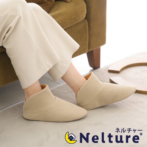 一雙淺米色、網格紋理的保暖腳踝室內拖鞋，鞋口內側為暖黃色，由柔軟材質製成，適合居家穿著。