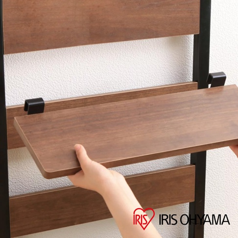 一隻手正在調整一個木紋置物台，該置物台固定在黑色金屬框架的頂天立地收納掛架上。