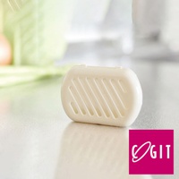 日製長效除臭防霉貼片盒，白色橢圓形塑膠盒，盒蓋有斜線通風孔，底部平坦，置於白色桌面，背景模糊。