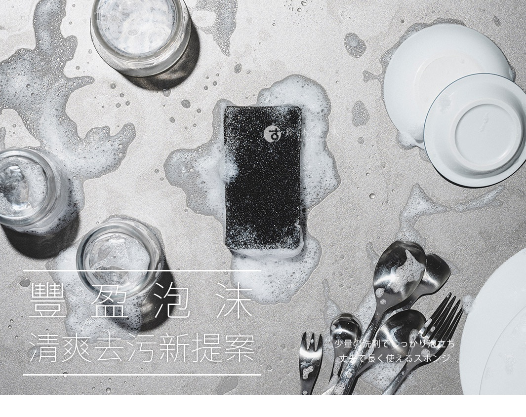 黑色超細纖維清潔海綿，周圍有豐富的白色泡沫，以及玻璃杯、白色盤子和銀色餐具。