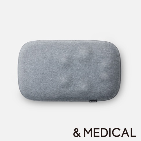 淺灰色布藝肩頸背按摩指壓枕，表面有細緻紋理，圓潤邊角，右下角有黑色的小標籤，標有白色字樣 & MEDICAL。