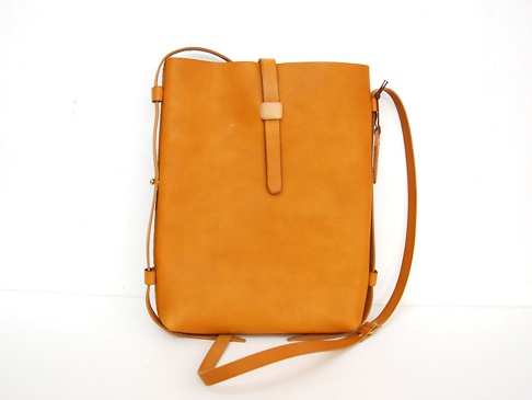 職人手作皮革散步直式單肩包 (CP-3)，採用淺棕色牛皮製成，包體為直立式長方形設計，正面中央有一條皮革束帶開合，側邊有可調節的細長皮革背帶。