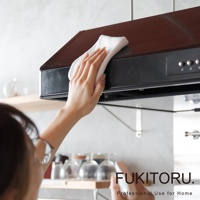 一隻手拿著白色超細纖維擦拭布，正在擦拭黑色抽油煙機的頂部。