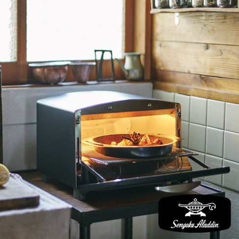 復古黑色多用途烤箱內，一個圓形烤盤盛有食物，烤箱門半開，內部散發溫暖光線。