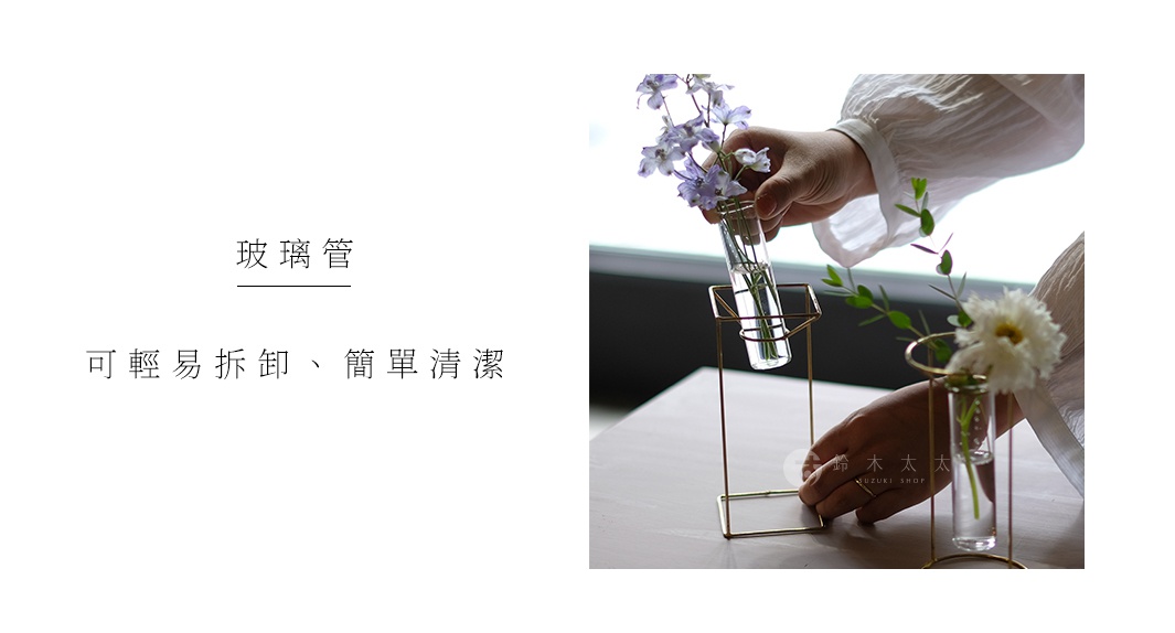 黃銅四角底座支撐著透明玻璃試管，試管內插有紫色和白色花朵與綠葉。