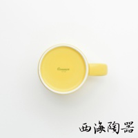 一個圓形黃色陶瓷馬克杯，杯底有「Common JAPAN」字樣，杯身有一條與杯底同色的手把。