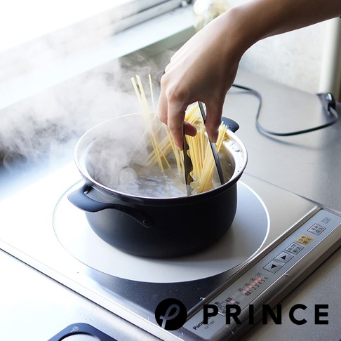 一雙黑色萬用料理麵食分菜夾，正在將煮沸的義大利麵從鍋中夾起。