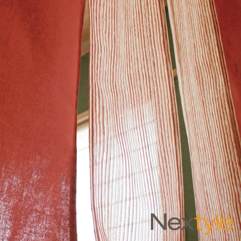 日製手作風四開式門簾，左側為素面磚紅色厚實布料，右側為帶有紅白色細條紋的半透明薄紗材質，營造出層疊的視覺效果。