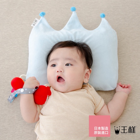 淺藍色皇冠造型嬰兒枕，枕頂有兩個藍色絨球裝飾，由柔軟布料製成，適合7至24個月嬰兒使用。