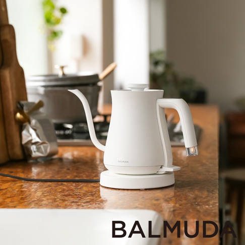 白色簡約手沖壺，帶有細長鵝頸壺嘴和人體工學提把，放置於同色系底座上，壺身印有BALMUDA Logo。