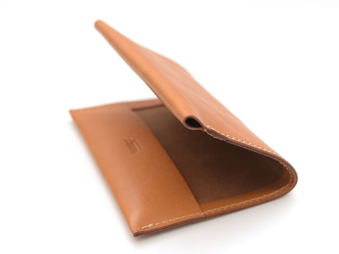 職人手作皮革翻蓋記事本書套，經典棕色，採用真皮材質，設計簡約，邊緣車縫細緻，翻蓋部分微微開啟，展示內部。