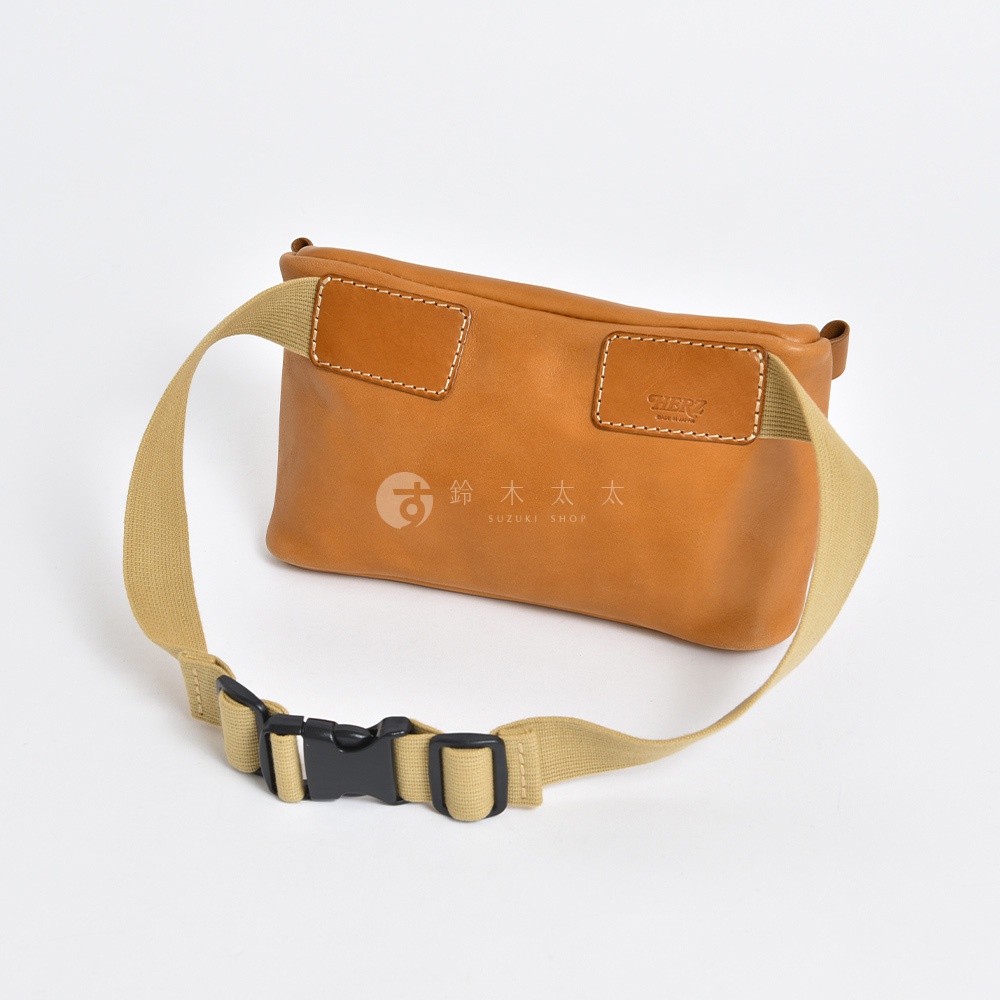 職人手作皮革兩用腰掛斜背包，淺棕色皮革，搭配卡其色織帶及黑色插扣，包身有縫線裝飾與品牌壓紋。