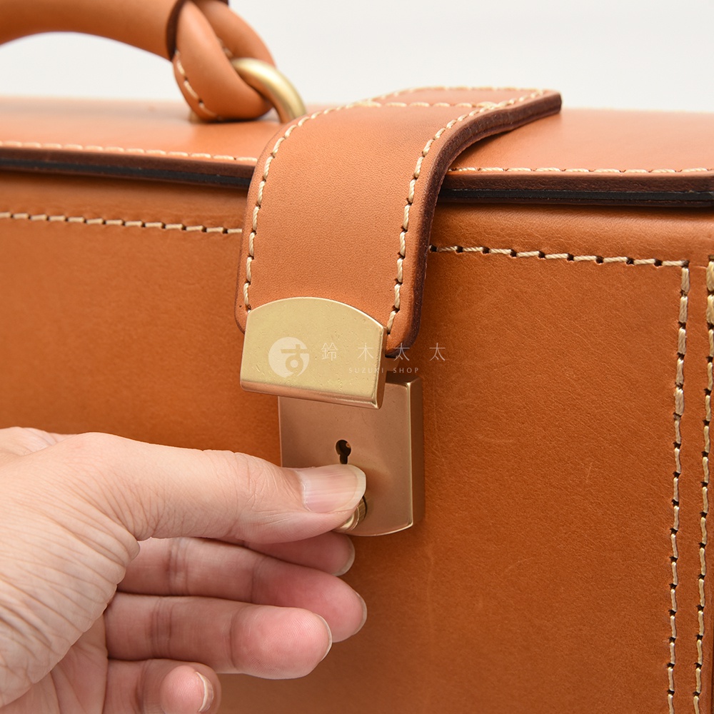 職人手作皮革機師箱，採用棕褐色皮革，搭配金色金屬鎖扣及提把，車線縫製精緻。