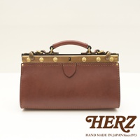 棕色皮革製成的復古口金兩用手提包，帶有金色金屬配件和提把。包包正面有盾牌形狀的皮革裝飾，整體呈現簡約經典的風格。