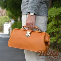 職人手作皮革長型迷你醫生包，採用淺棕色皮革，配有金色旋轉鎖扣和提把，精緻車縫線，經典醫生包造型。