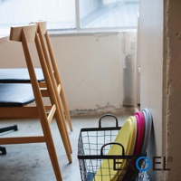 MARU PUNI 圓座墊，黃色、桃紅色、灰色，圓形，材質不明，堆疊於黑色金屬網籃中，靠牆擺放。