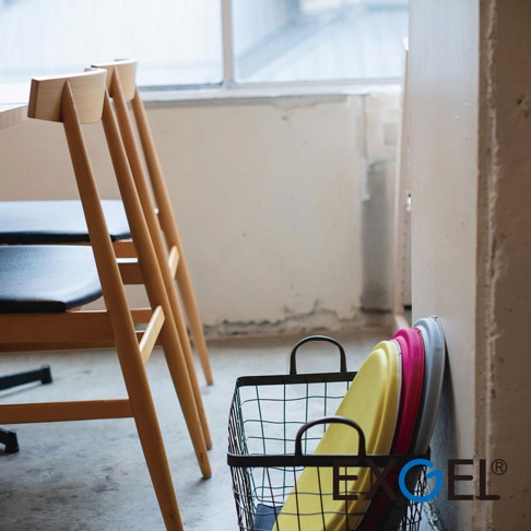 MARU PUNI 圓座墊，黃色、桃紅色、灰色，圓形，材質不明，堆疊於黑色金屬網籃中，靠牆擺放。