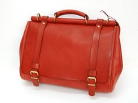 這款紅色皮革兩用側背包，採用光滑皮革材質，設有圓形手柄、兩條前袋扣帶、銅製釦環及固定扣，風格簡約。