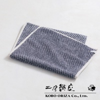 藍灰色棉麻混紡人字紋浴墊，邊緣有白色滾邊。