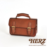 職人手作皮革雙扣兩用迷你肩背包，採用鞣製皮革製作，呈現溫潤的棕色調，包款設有雙皮帶與黃銅扣環，頂部有提把，適合肩背或手提。