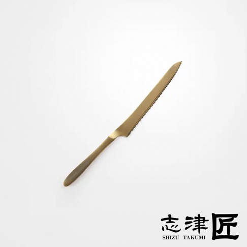 金色金屬鋸齒狀麵包刀，刀身光滑，刀柄末端有品牌標誌。