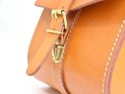 職人手作皮革皮扣單肩包，使用棕褐色皮革製作，搭配黃銅色金屬皮扣與車縫線，展現簡約風格。