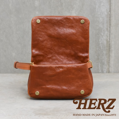 職人手作皮革Organ斜背包 G-92 S，棕色，翻蓋設計，以金色卯釘和皮帶扣固定，包身側面有品牌壓印。