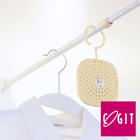 日製可掛式長效除臭防霉除濕貼片盒，淺黃色方形塑料盒，表面布滿圓形透氣孔，中央有可愛獅子圖案，附有掛環，懸掛於白色吊桿上，下方有白色衣物和衣架。