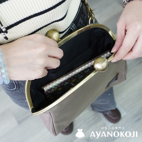 京都職人手作大玉口金斜背包，展示仕女手持打開的樣子，露出內部的筆記本。