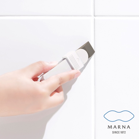 手持白色筆狀去污橡皮擦，其深灰色擦頭正在清潔白色磁磚縫隙。