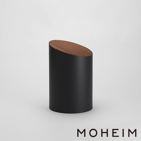 黑色的圓柱形垃圾桶，上方帶有傾斜的胡桃木蓋，風格簡約現代。