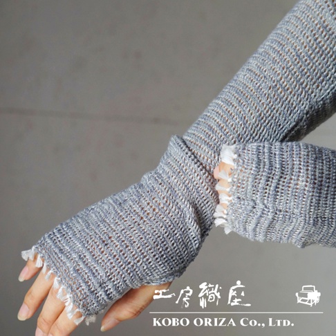 一雙灰色、網狀編織的輕柔有機棉遮陽袖套，帶有流蘇裝飾，覆蓋手部至手肘。