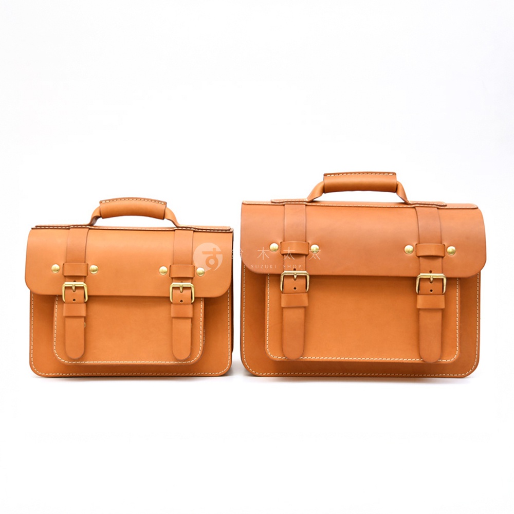 兩款棕褐色皮革單肩包，皆配有頂部提把、雙前袋、兩個金屬插釦和可調節背帶，展現經典雙扣設計。