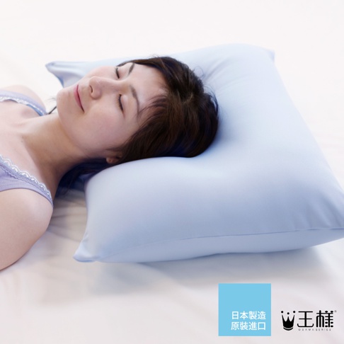 淺藍色「王樣の舒涼枕」枕頭，枕套為光滑的材質，一位女性仰臥，頭部枕在枕頭上，臉部表情安詳。