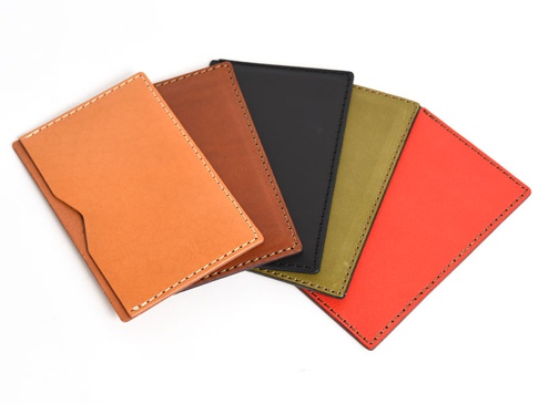 五款顏色各異的職人手作皮革存摺文件收納夾，包含淺棕色、深棕色、黑色、橄欖綠和紅色。皆為真皮材質，以白色車線縫製，設計簡約，可收納存摺或文件。