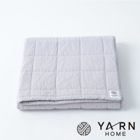 淺灰色格紋鋪棉浴巾，由脫脂棉混紡紗製成，表面有細緻的格紋縫線，左下角有品牌標誌。